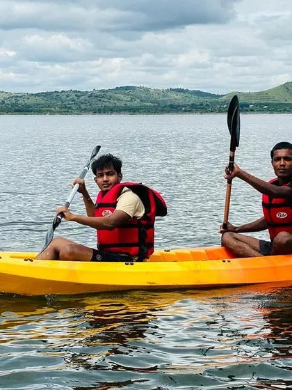 Two young men enjoying their time in a tandem kayak on the lake, all smiles during their adventure.