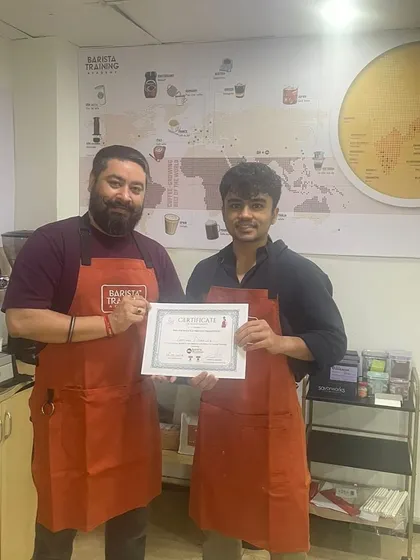 A student proudly receives their certificate upon completing the Go Abroad course, ready for their international coffee journey.