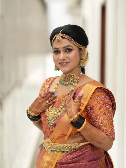A happy client looking beautiful for her wedding. She is wearing a classic temple jewellery set with a choker, haram, and matching jhumkas.