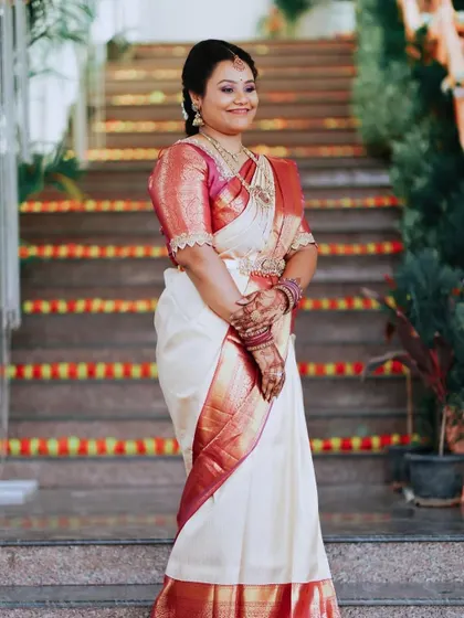 Meghana looking gorgeous as a wedding guest. Her makeup is fresh and radiant, complementing her beautiful off-white and maroon Kanchipuram saree.