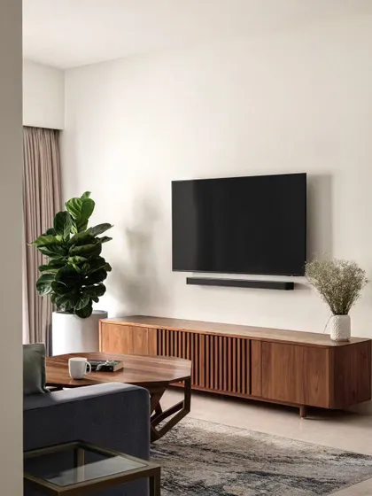 A clean and simple media unit setup. The floating wooden console keeps the floor clear and enhances the sense of space. A large fiddle-leaf fig plant adds a beautiful, natural element to the room.