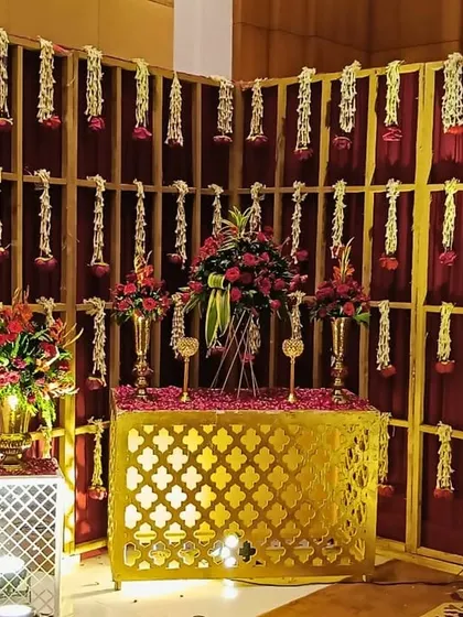 A golden touch of grandeur. This corner features a gold jali console, a backdrop of hanging florals, and rich red drapes, creating an ambiance of royalty.