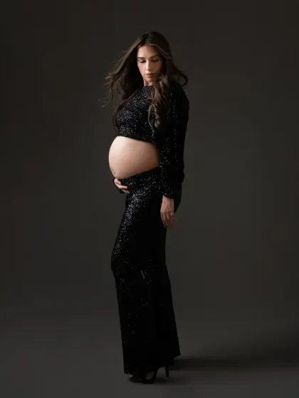 A full body profile in this stunning sequin outfit. The way the light catches the sequins adds texture and drama, creating a high fashion maternity portrait.