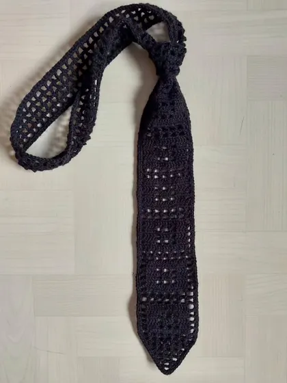 A flat-lay of the filet crochet tie, showing the full length and construction.