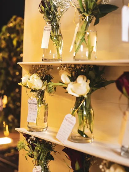 Another detail of the wishing well, showcasing the simple elegance of white flowers in glass bottles, each with a personal message tag for the celebrated couple.