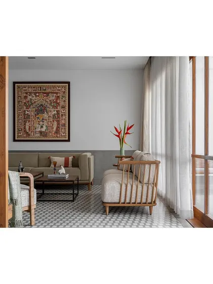 A calm living space with neutral-toned furniture, patterned floor tiles, and a large piece of textile art.