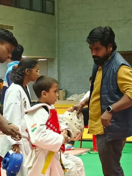 A coach helps a young athlete prepare for his Taekwondo match. The guidance and support of coaches are invaluable in helping players stay focused and perform their best.