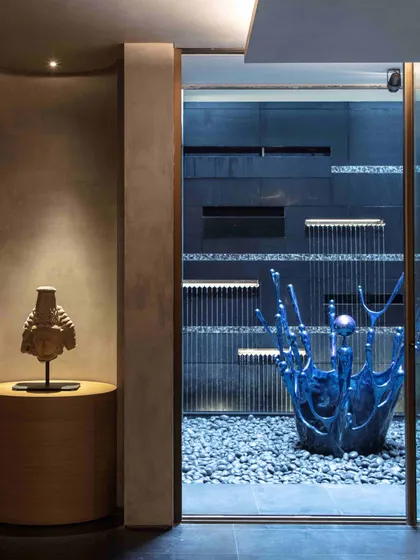 In the basement courtyard, a serene water feature is anchored by a vibrant blue sculpture by Alex Davis. The installation creates a tranquil focal point, blending the elements of water, stone, and contemporary art.