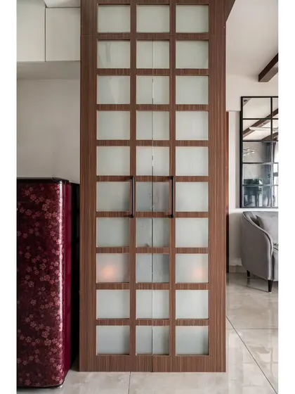 A discreet puja space enclosed by a latticed wood and frosted glass grid, camouflaging the hardware and blending with the home's modern design.