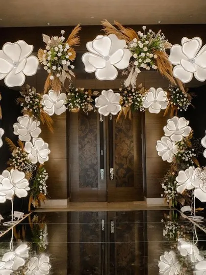 A straight-on view of the glowing floral entrance. The symmetrical design and reflective walkway create a powerful and inviting path, setting a magical tone for the event inside.