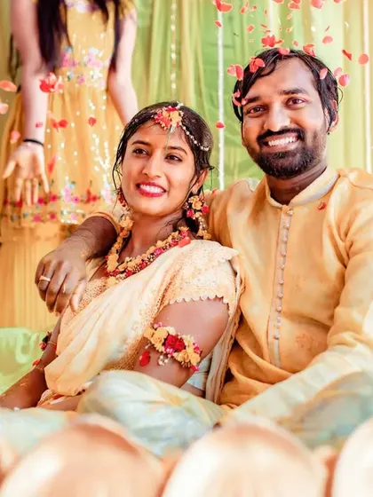 A sweet and happy moment of a couple sitting together after the Haldi rituals, surrounded by flowers.
