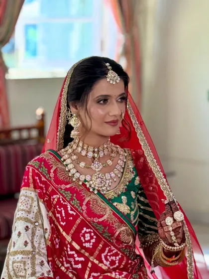 A three-quarter profile of the bride, highlighting the layered jewelry and the way the makeup ties the whole look together.