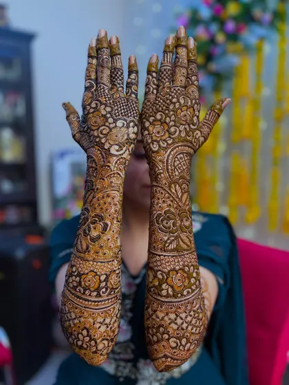 The bride showing off her full bridal henna, with intricate patterns covering her hands and arms.
