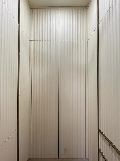 A direct view into the walk-in closet, showcasing the beautiful texture created by the vertical fluted panels. The off-white color keeps the space feeling bright and airy.