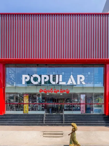 The completed facade of the Popular Shoe Mart. The vibrant red frame and vertically-lined ACP cladding create a modern and unmissable landmark, drawing customers in.