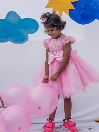 A full view of this classic pink party dress. The large satin bow and layered tulle skirt are signature elements that make this a favorite for birthdays and celebrations.