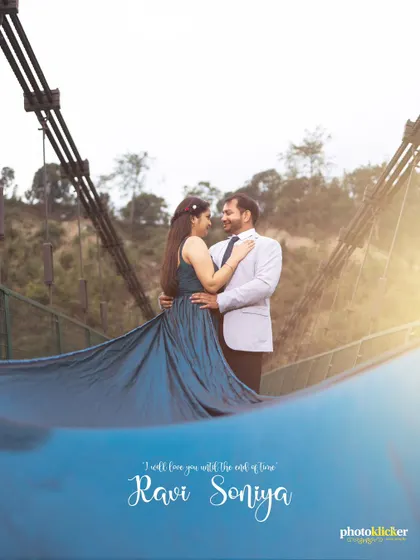An elegant pre-wedding photo on a suspension bridge, with the woman's long teal gown creating a beautiful wave effect in the foreground.