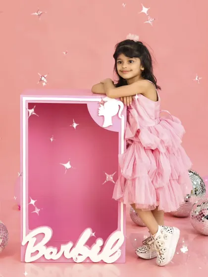 Leaning against her life-sized Barbie box, this little girl strikes a pose. It's a stylish and fun shot from her fifth birthday celebration.