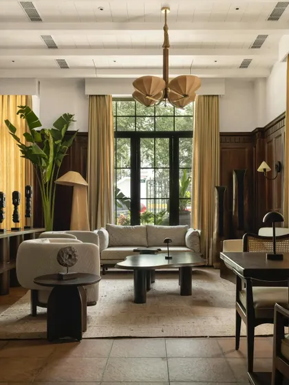 The lounge at Lord Elgin in Ludhiana, a space where colonial charm meets modern restraint. The room is characterized by rich wood paneling, light-toned contemporary furniture, and large windows that flood the space with natural light.