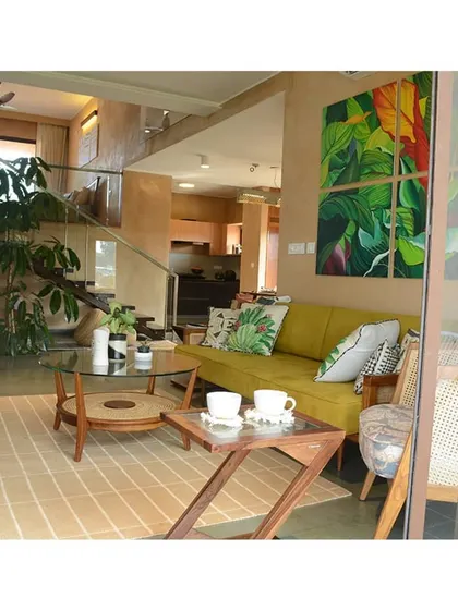 The living area is filled with natural light and indoor plants, enhancing the connection to the outdoors. The design emphasizes porosity and visual links to the surrounding greenery.