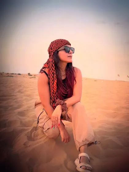 A candid shot while sitting on the sand dunes. The red and black headscarf added a pop of color to my neutral-toned desert safari outfit.