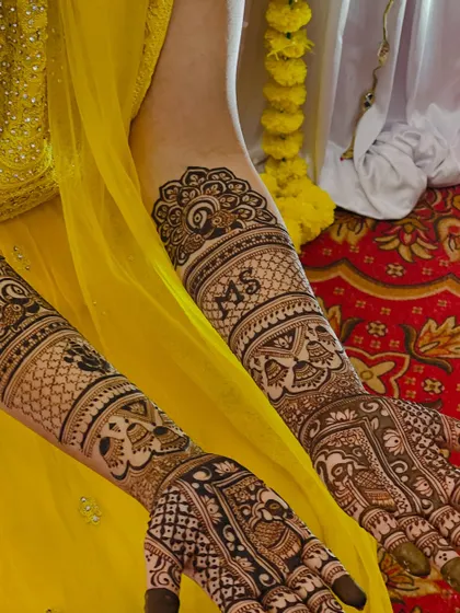 A close-up of the bridal mehendi, showing the "MS" initials and the intricate elephant and bell motifs.