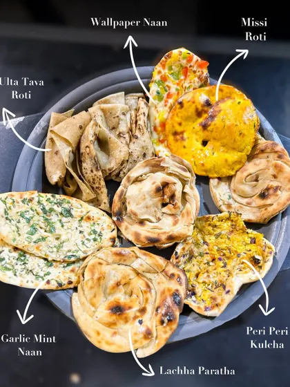 I take pride in our artisanal Indian breads, each one handcrafted to perfection. This platter showcases the variety I offer, from the flaky Lachha Paratha and soft Ulta Tava Roti to the flavorful Garlic Mint Naan and spicy Peri Peri Kulcha.