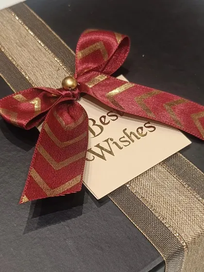 The elegant black gift box is tied with a red and gold ribbon and a 'Best Wishes' tag, making the presentation as special as the gift inside.