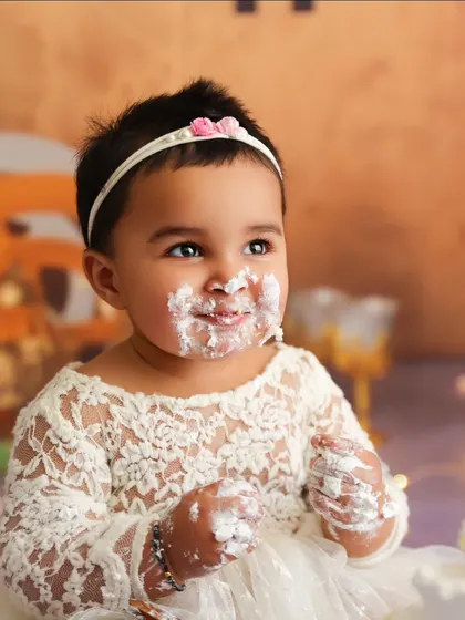 A sweet, frosting-covered smile captured during a beautifully styled cake smash session.
