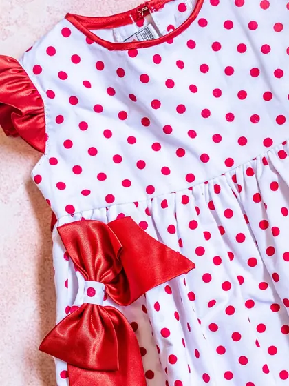 A classic red and white polka dot dress. This close-up shows the ruffled satin sleeves and the oversized double bow that gives this dress a fun, retro feel.