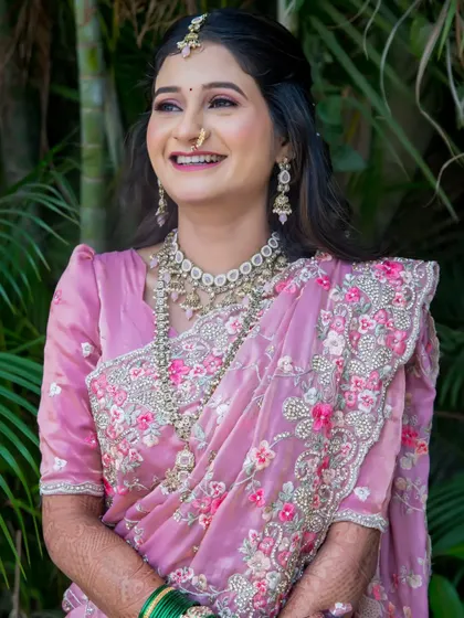 A classic bridal portrait, capturing the bride's radiant smile and the stunning detail of her embroidered pink saree.
