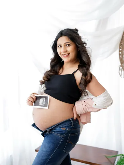 A proud and happy mama-to-be showing off her sonogram. Her casual and comfortable style makes this a relatable and sweet portrait.