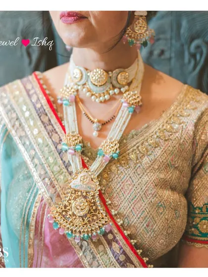 A close-up of a custom-made pastel polki choker and long necklace set. The soft pink and blue meenakari work was designed to match the bride's multi-hued lehenga.