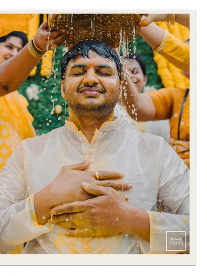 The groom closes his eyes in blissful surrender as he is showered with water and blessings during his Haldi ceremony.