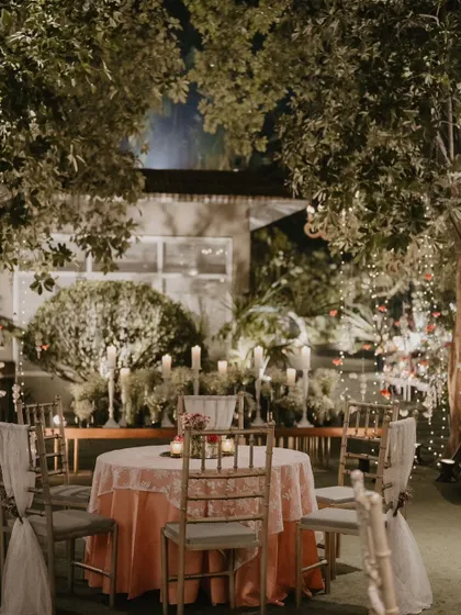 A quiet, romantic table setting surrounded by trees and fairy lights.
