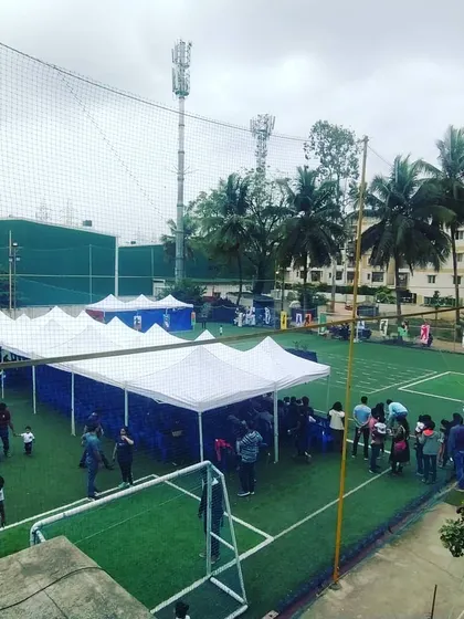 An aerial view of an outdoor football tournament setup, showing the organized arrangement of tents and seating on an artificial turf field for players and spectators.