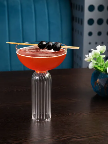 This cocktail is photographed in a way that highlights its unique, modern glassware. The clean composition and ambient lighting make it look sophisticated and chic.