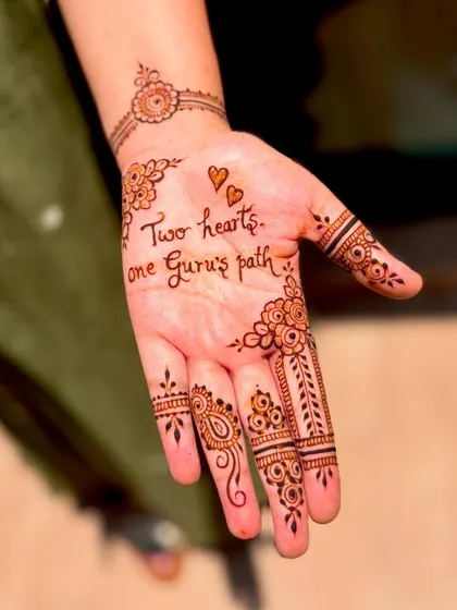 A close-up of the custom quote "Two hearts, one Guru's path" from Gurpriya's engagement mehendi.