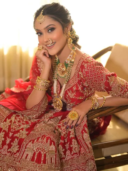 A happy bride is the prettiest bride. Her smile shows how comfortable and beautiful she feels in her complete look, from the intricate red lehenga to the flawless, glowing makeup.