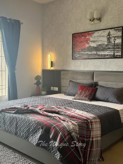 Another angle of the transformed son's bedroom, showing the grey upholstered bed with a fluted headboard panel. A striking piece of art with a pop of red adds a dynamic touch to the otherwise serene space.
