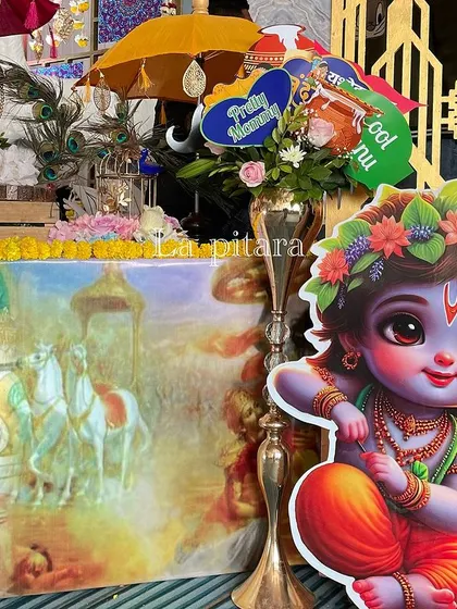 A close-up of the stage decor, showing a cute Little Krishna cutout and other thematic props.