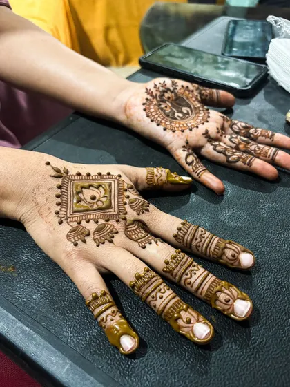 A pair of unique guest designs. One hand features a square lotus motif, while the other has a traditional elephant design.
