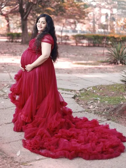 This stunning red tulle gown is a favorite for maternity photoshoots. Its long, ruffled trail creates a dramatic effect, while the comfortable design beautifully accommodates your baby bump, making it a perfect rental for capturing those precious memories.