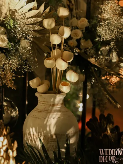 Even the smallest details are designed to capture the light. This arrangement features dried botanicals in a textured white vase, perfectly placed to catch the dramatic shadows and highlights of the event lighting.