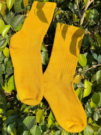 A pair of cozy socks dyed a vibrant yellow using marigold petals. Who says everyday essentials have to be boring? These are a little ray of sunshine for your feet.