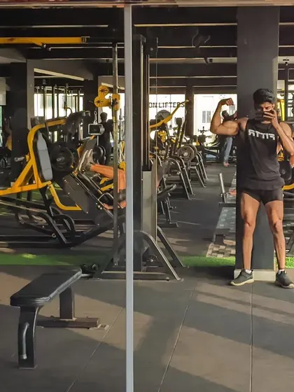 Sweat now, shine later. A bicep flex in a gym mirror selfie.