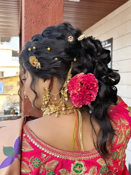 A detailed view of a traditional bridal hairstyle. This intricate bun is adorned with fresh flowers and gold accessories, a classic choice for a Maharashtrian wedding.