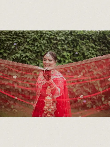 The bride smiles as she holds her red veil, creating a classic and timeless portrait.