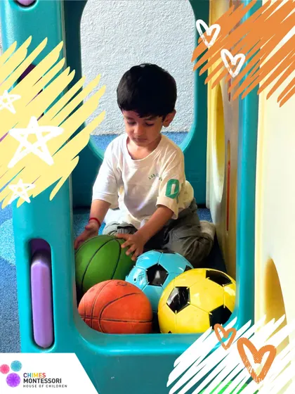 A young boy explores different types of balls in a playhouse. This unstructured play allows for imaginative exploration and the development of motor skills.