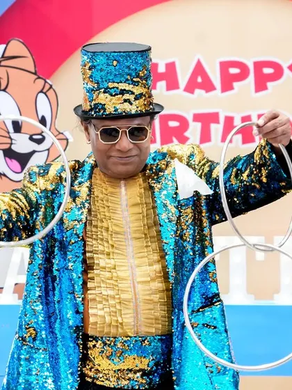 A magician in a dazzling sequined costume performing a classic ring trick for the audience at a Tom & Jerry themed party.
